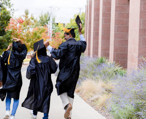 The four multi-ethnic graduates walk out of the auditorium to meet their families after the graduation ceremony.  They are glad to be done.